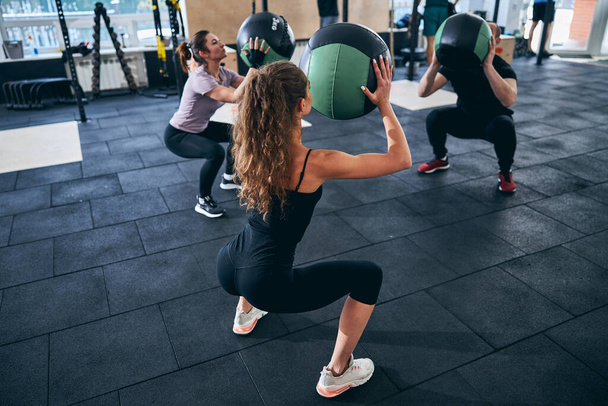 Three people doing squats with stability balls - Photo, Image