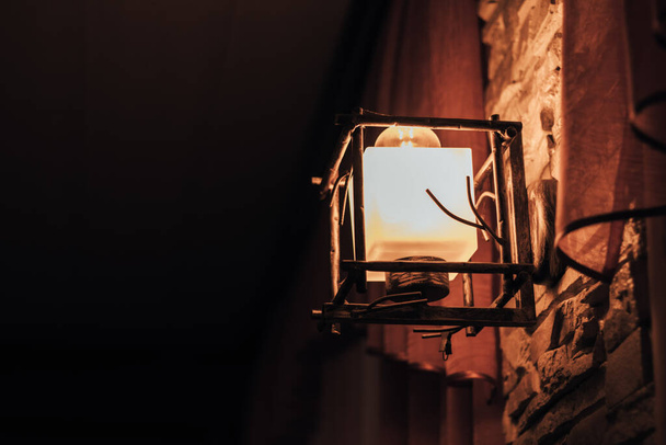 lampe jaune sur le mur dans un style vintage dans une pièce sombre  - Photo, image