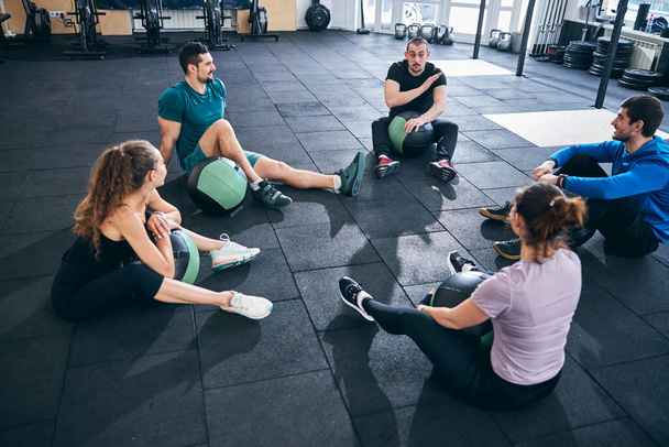 Four athletes listening to their fitness coach - Zdjęcie, obraz