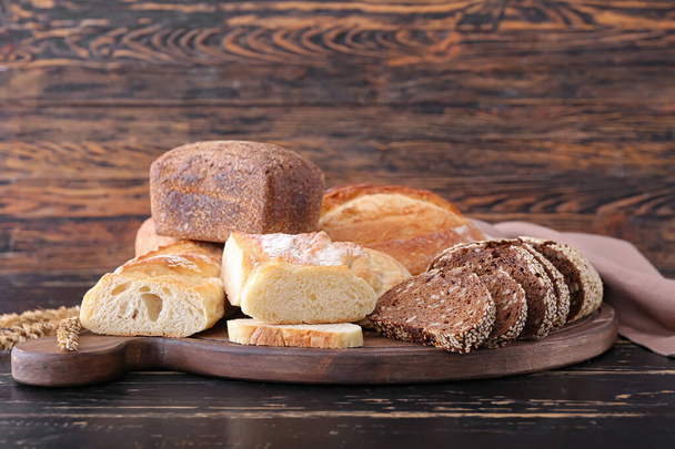 Board with fresh different bread on wooden background - Fotoğraf, Görsel