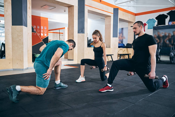 Two people with dumbbells repeating the exercise after the instructor - Photo, Image