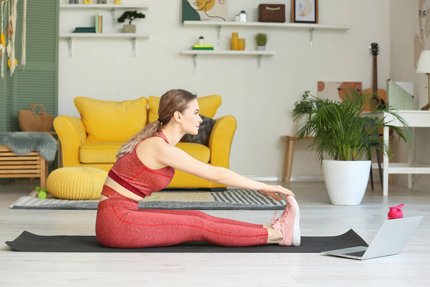 Sportos fiatal nő laptop gyakorló jóga otthon zárlat alatt - Fotó, kép