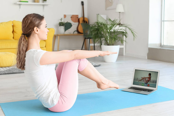 Sporty young woman with laptop practicing yoga at home during lockdown - Foto, immagini
