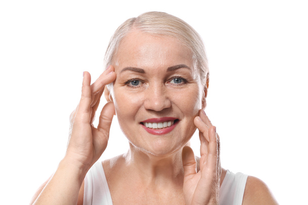 Mature woman giving herself face massage on white background - Photo, Image