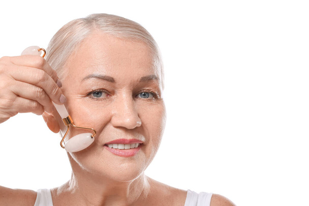 Mature woman with facial massage tool on white background - Zdjęcie, obraz
