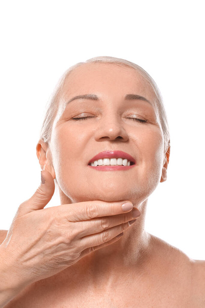 Femme mûre se donnant massage du visage sur fond blanc - Photo, image
