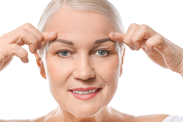volwassen vrouw geven zichzelf gezicht massage op witte achtergrond - Foto, afbeelding