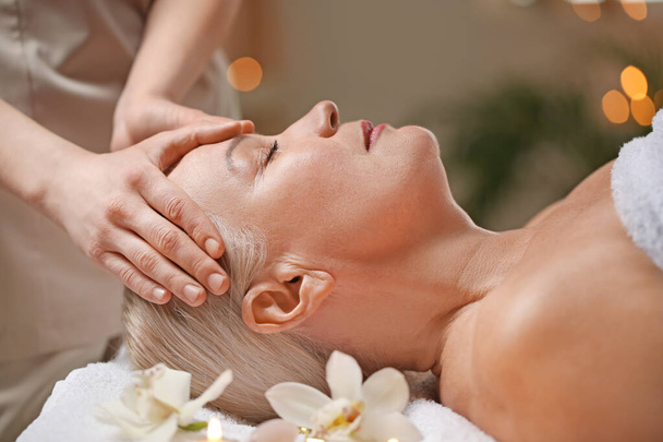 Mujer madura recibiendo masaje facial en salón de belleza - Foto, imagen