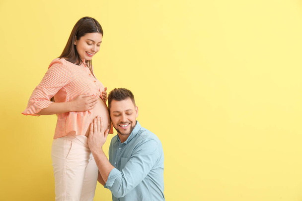 Schöne schwangere Paar auf farbigem Hintergrund - Foto, Bild