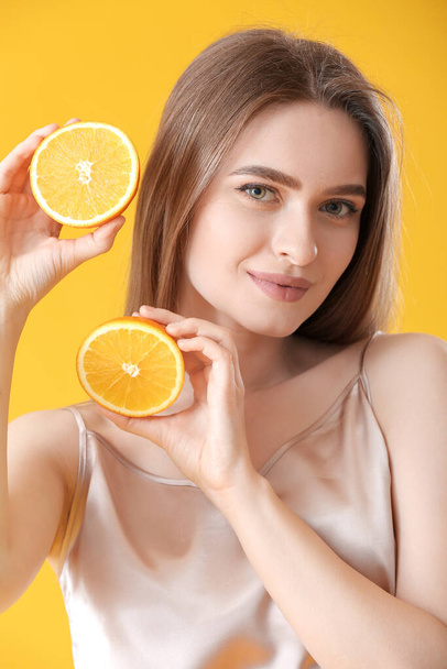 Beautiful young woman with orange on color background - Photo, Image