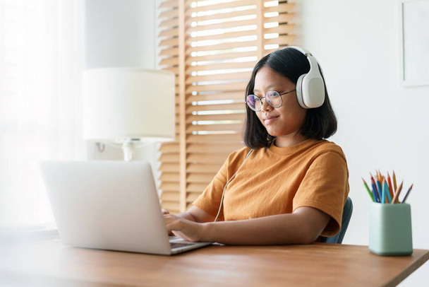 Asian student woman learning online using a computer laptop with headphones while sitting workplace on a table at home in the morning. Concept online learning at home - Фото, изображение