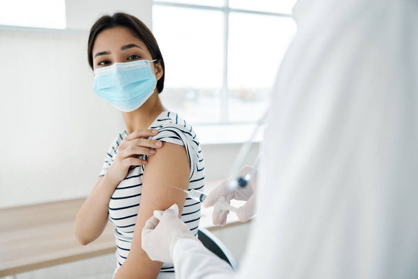 fehér köpenyes orvos adja be az injekciót egy kórházi kovid védőoltásban részesülő nő vállába. - Fotó, kép