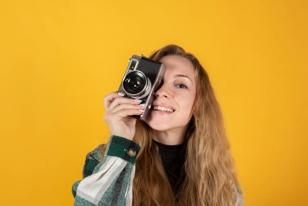 bella donna bionda con una macchina fotografica, su sfondo giallo - Foto, immagini