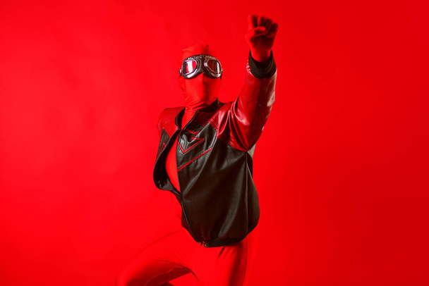 A funny super hero in a red leotard and protective glasses flying forward. - Foto, immagini