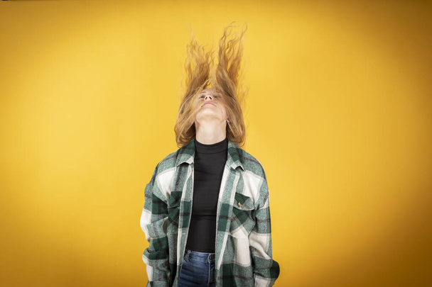 blonde woman with hair in the air, yellow background - 写真・画像