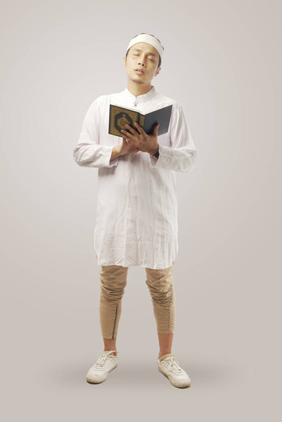 portrait of religious Asean muslim man holding Quran isolated in white background. - Фото, изображение