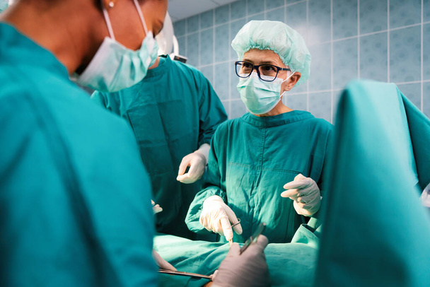 Group of surgeon doctor team at work in operating room in hospital - Foto, afbeelding