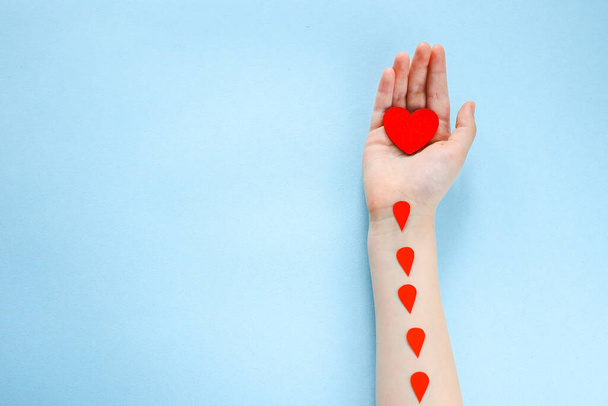 red heart in a child's hand on a blue background, charity and care, blood donation - Φωτογραφία, εικόνα