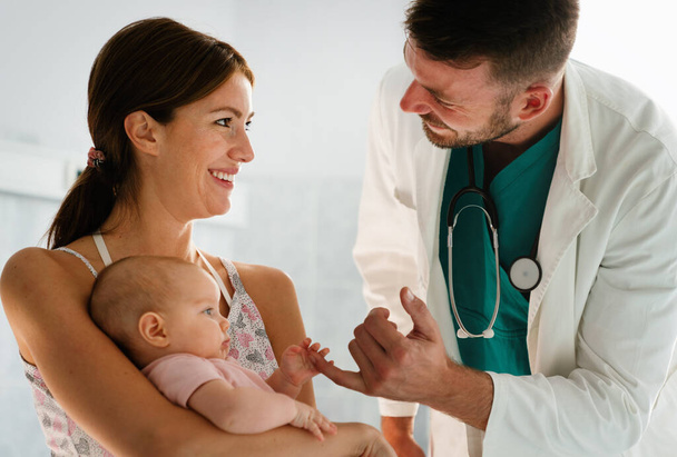 Mother holding baby for pediatrician doctor to examine. People healthcare concept - Фото, изображение