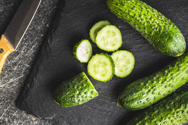 Sliced fresh green cucumbers on cutting board. Top view. - Foto, imagen
