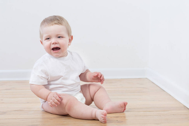 baby crying sitting on wooden floor - Foto, immagini
