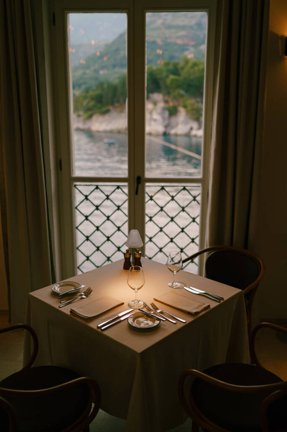 窓の近くのレストランで正方形のテーブルを提供し、海と山を見下ろす. - 写真・画像