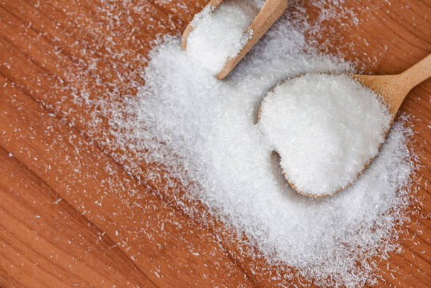 Glutaminian sodu na łyżce i drewnianym tle stołu, glutaminian sodu do przypraw spożywczych - Zdjęcie, obraz