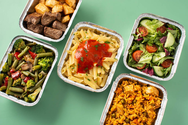 Tolga il cibo sano in scatole di lamina di metallo su sfondo verde - Foto, immagini