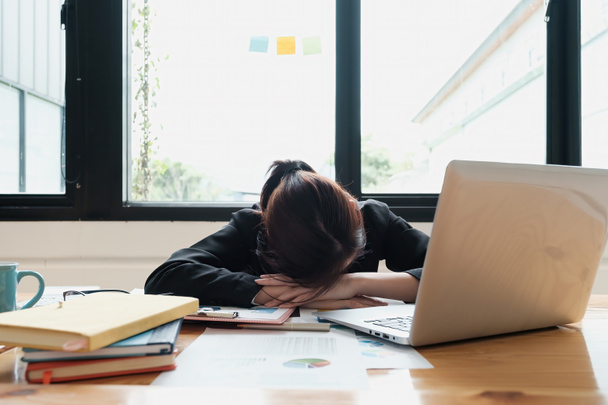 プロジェクトの締め切り中は、朝まで働くストレスの多いビジネス女性と、オフィスのテーブルで疲れて眠る。財務、会計、税務、監査の概念. - 写真・画像