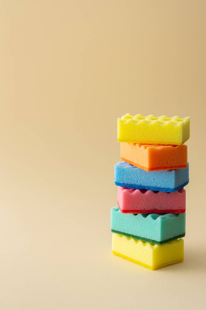 Pila de esponjas lavavajillas multicolores sobre fondo beige neutro, hogar de cocina y concepto de limpieza - Foto, Imagen