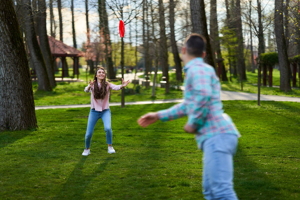 Casual dressed young couple playing freesbie in the park  - Foto, Imagen