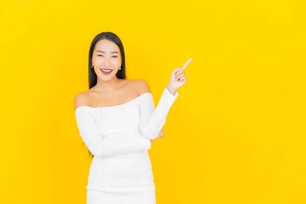 Retrato hermosa joven negocio asiático mujer con sonrisa y acción amarillo fondo - Foto, Imagen
