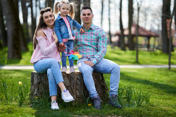 Happy young family of mother, father and little daughter having a great quality time in the park in the spring - Fotoğraf, Görsel