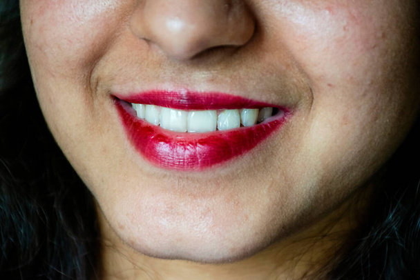 Foto en stock de 20 a 25 años hermosa sonrisa chica india con dientes blancos sanos, niña aplicar lápiz labial de color rosa oscuro, fondo borroso. - Foto, imagen