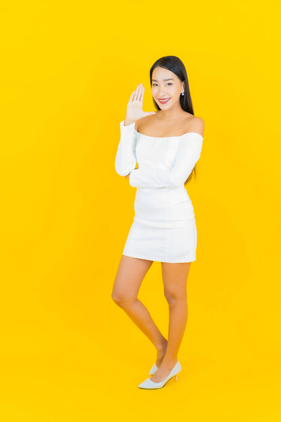 Portrait beautiful young business asian woman with smile and action yellow background - Foto, afbeelding