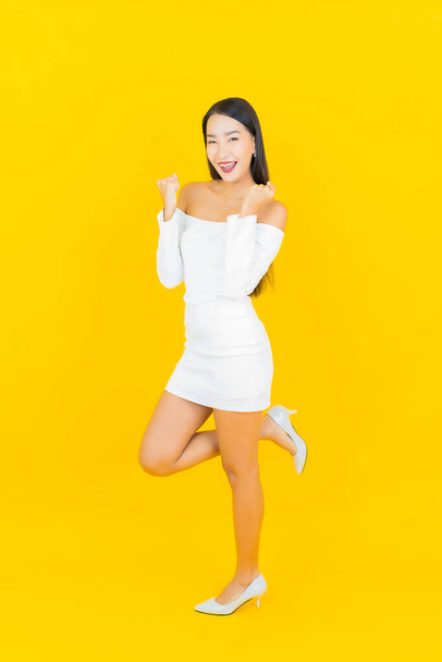 Porträt schöne junge Geschäft asiatische Frau mit Lächeln und Aktion gelben Hintergrund - Foto, Bild