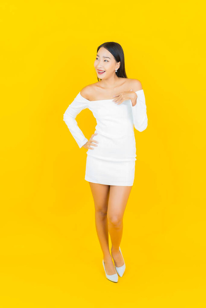 Portrait beautiful young business asian woman with smile and action yellow background - Foto, Imagen