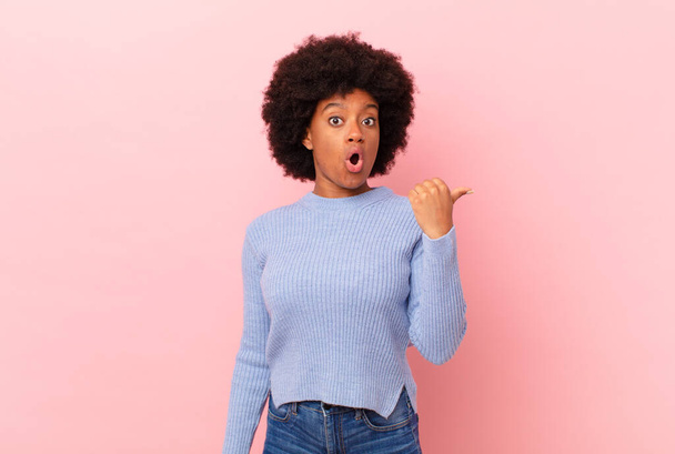 afro black woman looking astonished in disbelief, pointing at object on the side and saying wow, unbelievable - Photo, image