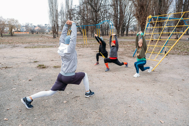 Group fitness workout classes outdoors. Socially Distant Outdoor Workout Classes in public parks. Three women and man training together in the public park. Health, wellness and community concept - Fotografie, Obrázek