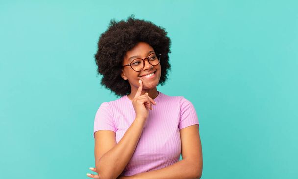 afro black woman smiling happily and daydreaming or doubting, looking to the side - Фото, изображение