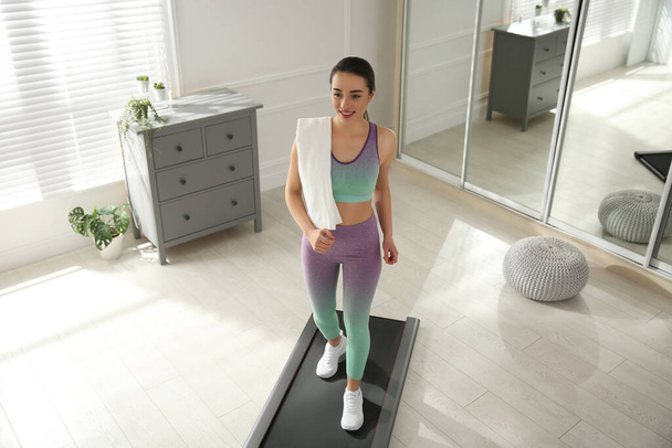 Sporty woman training on walking treadmill at home - Фото, изображение
