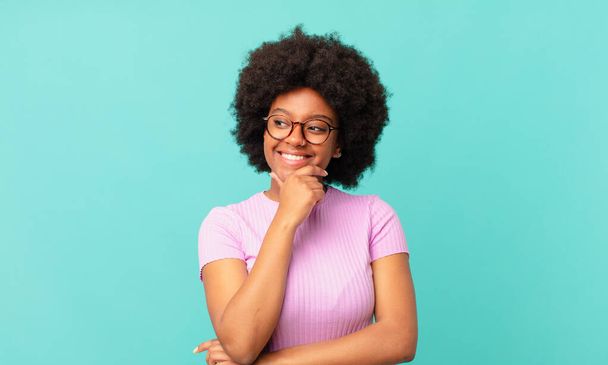 afro black woman smiling with a happy, confident expression with hand on chin, wondering and looking to the side - Фото, изображение