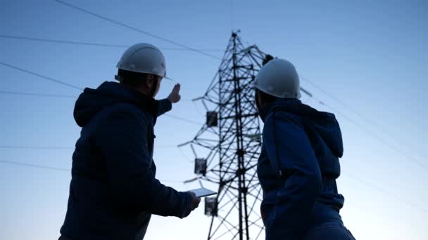 Teamwork and engineers, partners shaking hands, good work. Power workers in protective white helmets are checking power line online using computer tablet. Business concept. Woman and man work together - Footage, Video