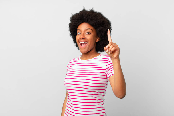 afro black woman feeling like a happy and excited genius after realizing an idea, cheerfully raising finger, eureka! - Valokuva, kuva