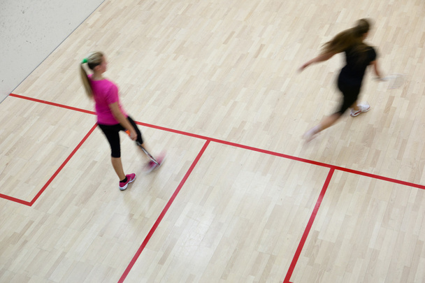 Two female squash players in fast action on a squash court (motion blurred image; color toned image) - Valokuva, kuva