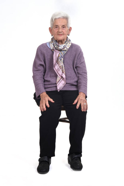 вид спереду старшої жінки, що сидить на стільці на фоні
 - Фото, зображення