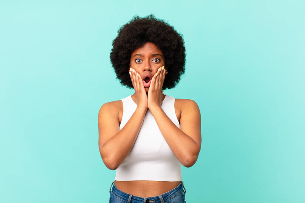 afro black woman feeling shocked and scared, looking terrified with open mouth and hands on cheeks - Φωτογραφία, εικόνα