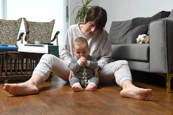 matka z dzieckiem siedzi na drewnianej podłodze w domu - Zdjęcie, obraz