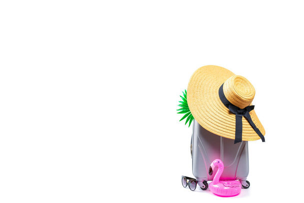 Nyári ünnepi poszter. Női kiegészítők utazó: bőrönd, szalmakalapos, napszemüveg, flamingó elszigetelt fehér háttér üres hely a szöveg. Nyári vakáció és termékreklám koncepció - Fotó, kép