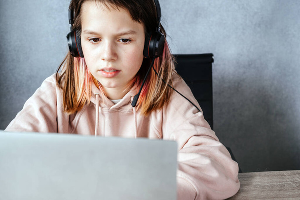 Genç kız internette ödevini yapıyor ve kulaklık dinliyor.. - Fotoğraf, Görsel